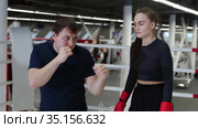 Male boxing coach shows the punch technic to his woman trainee. Стоковое видео, видеограф Константин Шишкин / Фотобанк Лори