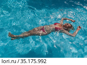 Beautiful woman floating in a swimming pool. Стоковое фото, фотограф Tetiana Chugunova / Фотобанк Лори