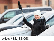 Happy and laughing woman with snow brush, waving her hand and looking at camera, winter season. Стоковое фото, фотограф Кекяляйнен Андрей / Фотобанк Лори