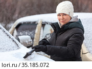 Woman removing snow from car with brush at winter season. Стоковое фото, фотограф Кекяляйнен Андрей / Фотобанк Лори