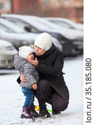 Young mom comforts the child after falling down on slippery road, hugging a toddler. Стоковое фото, фотограф Кекяляйнен Андрей / Фотобанк Лори