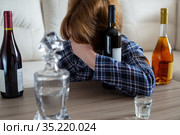 Drunk woman sitting at table with bottles of wine. Стоковое фото, фотограф Володина Ольга / Фотобанк Лори