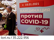 Информационный баннер о начале массовой вакцинации от новой коронавирусной инфекции COVID-19 с 18 января 2021 года вакциной Спутник V в мобильном пункте вакцинации в ГУМе города Москвы, Россия. Редакционное фото, фотограф Николай Винокуров / Фотобанк Лори