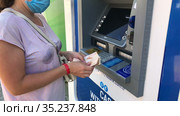 Woman in safety mask uses ATM, counts Turkish liras in hands. Group of ATM of different banks is for tourists withdraw cash. Alanya, Turkey (2021 год). Редакционное видео, видеограф Кекяляйнен Андрей / Фотобанк Лори