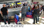 Passengers are waiting for luggage in airport terminal without keeping a social distance. Notice boards asking them to keep a social distance. Antalya, Turkey (2021 год). Редакционное видео, видеограф Кекяляйнен Андрей / Фотобанк Лори