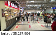 People stand in queue in Burger King store in food court in the Antalya International airport. Buyers in safety masks keep social distance during Covid-19 epidemic. Antalya, Turkey (2021 год). Редакционное видео, видеограф Кекяляйнен Андрей / Фотобанк Лори