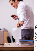 Young male employee stapling paper in the office. Стоковое фото, фотограф Elnur / Фотобанк Лори