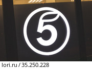 Супермаркет "Пятерочка". Крупно вечерняя подсветка логотипа "5 в круге" на стекле витрины (2021 год). Редакционное фото, фотограф Grigory_Gez / Фотобанк Лори