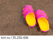 Детские розовые сабо стоят на песчаном пляже около воды. Children's pink clogs stand on a sandy beach near the water. Стоковое фото, фотограф Мария / Фотобанк Лори