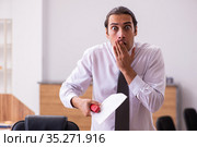 Young male employee stapling paper in the office. Стоковое фото, фотограф Elnur / Фотобанк Лори