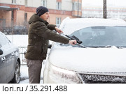 Caucasian driver removing snow under rubber wipers of his suv at winter time. Стоковое фото, фотограф Кекяляйнен Андрей / Фотобанк Лори
