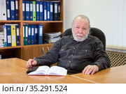 Grey hair and beard professor sitting at the table in his cabinet with notebook, Caucasian elderly man. Стоковое фото, фотограф Кекяляйнен Андрей / Фотобанк Лори