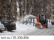Трактор убирает снег в московском дворе после снегопада (2021 год). Редакционное фото, фотограф Наталья Николаева / Фотобанк Лори