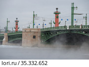 Дворцовый мост на фоне Ростральных колон морозным февральским днем. Санкт-Петербург (2021 год). Редакционное фото, фотограф Виктор Карасев / Фотобанк Лори