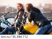 Two European women motorcyclists talking cheerfully while sitting on their motorcycles. Стоковое фото, фотограф Кекяляйнен Андрей / Фотобанк Лори