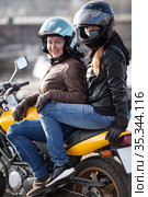 Girlfriend a passenger sitting behind female motorcyclist on a motorbike, cheerful females riding on the urban streets. Стоковое фото, фотограф Кекяляйнен Андрей / Фотобанк Лори