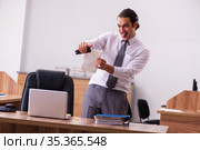 Young male employee stapling paper in the office. Стоковое фото, фотограф Elnur / Фотобанк Лори