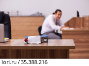 Young male employee stapling paper in the office. Стоковое фото, фотограф Elnur / Фотобанк Лори