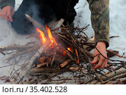 Турист подбрасывает в костер дрова. Стоковое фото, фотограф Анатолий Матвейчук / Фотобанк Лори