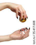 Female hand with black nails manicure and golden spiked massage ball in fingers. Стоковое фото, фотограф Сергей Пристяжнюк (Serg Zastavkin) / Фотобанк Лори