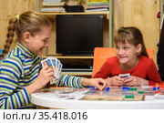 Две девочки радостно смеются играя за столом в настольные игры. Стоковое фото, фотограф Иванов Алексей / Фотобанк Лори