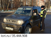 Инспектор дорожно-патрульной службы полиции проверяет документы водителя остановленного автомобиля (2016 год). Редакционное фото, фотограф Free Wind / Фотобанк Лори