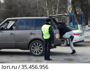 Инспектор дорожно-патрульной службы полиции проверяет багажник остановленного автомобиля (2016 год). Редакционное фото, фотограф Free Wind / Фотобанк Лори