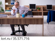 Old male employee suffering from radiculitis at workplace. Стоковое фото, фотограф Elnur / Фотобанк Лори