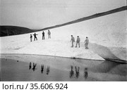 Несколько людей гуляют на краю ледника, поход к берегу реки по холмам частично покрытым льдом, путешественники отражается в воде, Чукотка, 1970. Редакционное фото, фотограф Варфоломей Тетерин / Фотобанк Лори