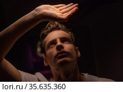 The guy covers his face with his palm from the light of the lamp. Стоковое фото, фотограф Женя Канашкин / Фотобанк Лори