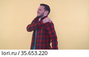 Young man in red shirt suffering from shoulder pain massaging it with his right hand. Стоковое видео, видеограф Mihail Mihaylov / Фотобанк Лори