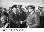 Встреча летчиков на взлётно-посадочной полосе, один из пилотов жмёт руку другому, девочка с пионерским галстуком на переднем плане, Якутия, 1960. Редакционное фото, фотограф Варфоломей Тетерин / Фотобанк Лори