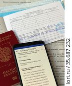 Российский паспорт, смартфон с открытым сайтом государственных услуг, сертификат о проведении вакцинации против COVID-19 (2021 год). Редакционное фото, фотограф Цибаев Алексей / Фотобанк Лори