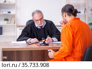 Old male judge meeting with young captive in courthouse. Стоковое фото, фотограф Elnur / Фотобанк Лори