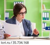 Young female employee very busy with ongoing paperwork. Стоковое фото, фотограф Elnur / Фотобанк Лори