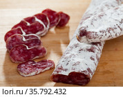 Slicing delicious Spanish smoked sausage fuete. Стоковое фото, фотограф Яков Филимонов / Фотобанк Лори