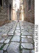 Detail shot of female legs wearing comfortable travel sandals walking on old medieval cobblestones street dring sightseeing city tour. Travel, tourism and adventure concept. Стоковое фото, фотограф Matej Kastelic / Фотобанк Лори