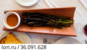 Calcots onions served on plate with Romesco sauce – traditional Catalan dish. Стоковое фото, фотограф Яков Филимонов / Фотобанк Лори