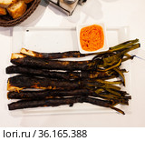 Calcots onions served on plate with Romesco sauce - traditional Catalan dish. Стоковое фото, фотограф Яков Филимонов / Фотобанк Лори