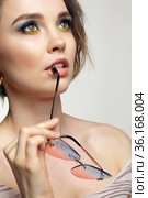 Portrait of young woman bites the bow of glasses. Стоковое фото, фотограф Сергей Пристяжнюк (Serg Zastavkin) / Фотобанк Лори