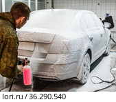Мужчина покрывает пеной автомашину на мойке (2021 год). Редакционное фото, фотограф Игорь Низов / Фотобанк Лори