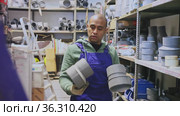 Cheerful Latino workman preparing for pipework routing, choosing supplies in shop of building materials. Стоковое видео, видеограф Яков Филимонов / Фотобанк Лори