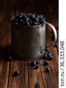 Fresh blueberries are pouring out of mug on a wooden background. Стоковое фото, фотограф Александр Иванов / Фотобанк Лори