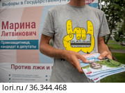Волонтер предвыборного штаба Марины Ливинович кандидата в депутаты в Государственную Думу РФ от партии "Яблоко" раздает агитационные листовки в городе Москве, Россия (2021 год). Редакционное фото, фотограф Николай Винокуров / Фотобанк Лори