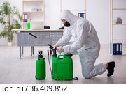 Young male contractor disinfecting office during pandemic. Стоковое фото, фотограф Elnur / Фотобанк Лори