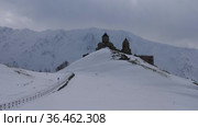 View of the Trinity Church in Gergeti at the foot of Kazbek, towering over the village of Stepantsminda, Georgia. Стоковое видео, видеограф Яков Филимонов / Фотобанк Лори