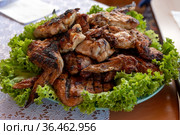 Куриные крылышки, жареные на решётке гриля, лежат на листьях зелёного салата на фарфоровом блюде, готовые к употреблению. Стоковое фото, фотограф Светлана Попова / Фотобанк Лори