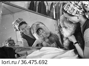 Портрет молодой женщины и ребёнка возле зеркала, девушка примеряет девочке тёплый капюшон из натурального меха, они находятся в помещении, село Уэлен, Чукотка. Редакционное фото, фотограф Варфоломей Тетерин / Фотобанк Лори