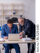 Old boss and young male employee in bullying concept. Стоковое фото, фотограф Elnur / Фотобанк Лори