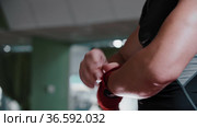 Young man boxer binds his palm and fingers with red bandages and stands in a protective stance. Стоковое видео, видеограф Константин Шишкин / Фотобанк Лори